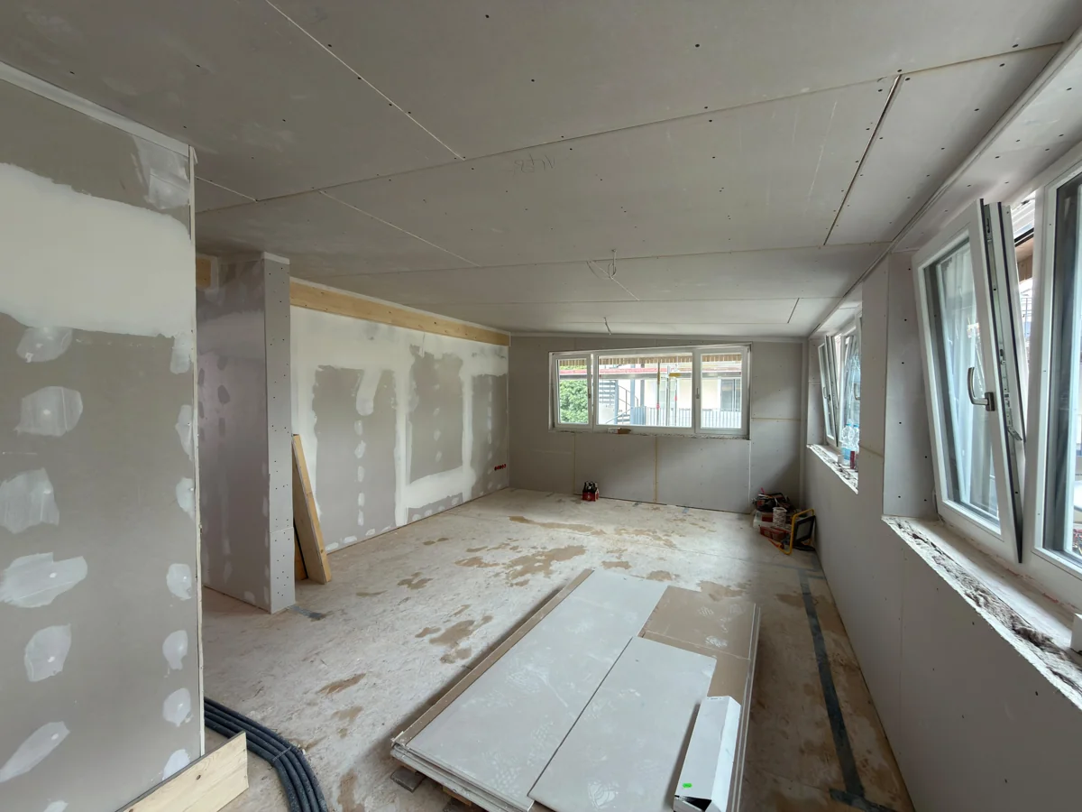 Großer Raum mit montierten Wandplatten, Fenstern und sichtbaren Plattenstößen