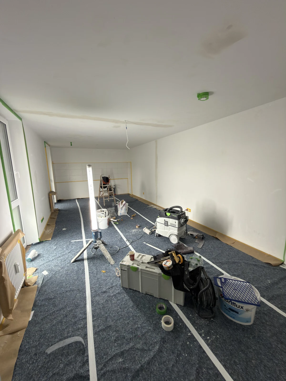 Wohnung im ersten Arbeitsstand mit abgedecktem Boden und Arbeitsmaterial